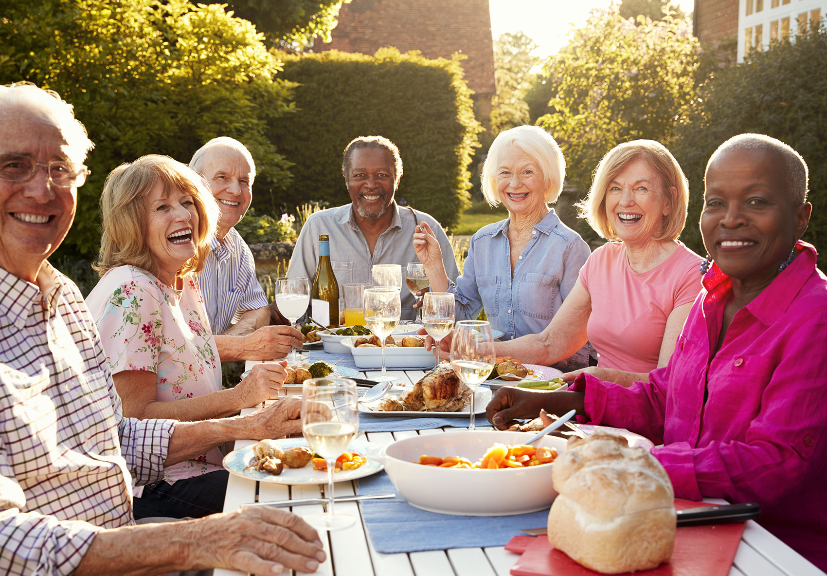 Senior citizens sit at table outside for a meal